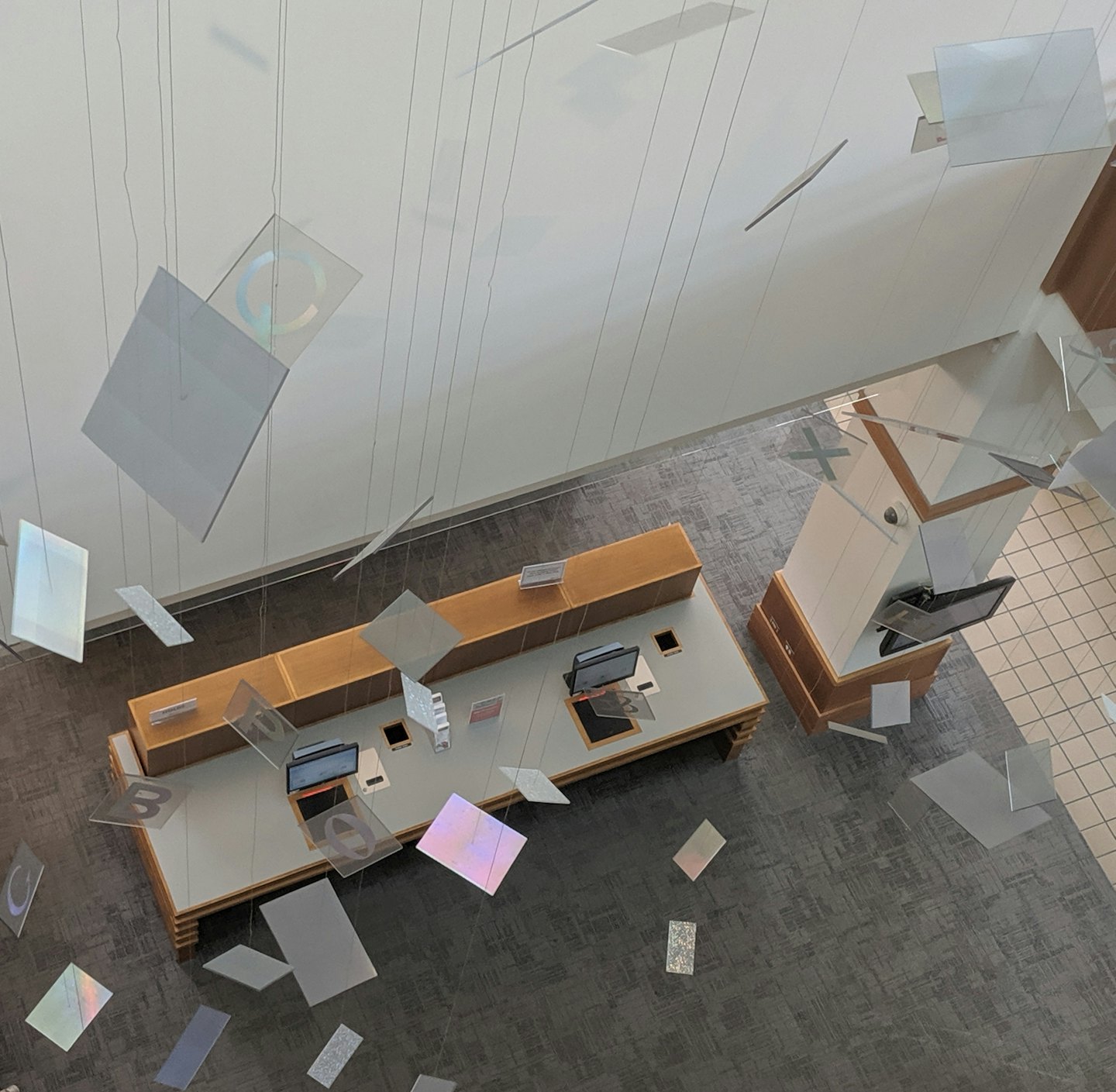Modern reception area with two desks and suspended decorative panels.
