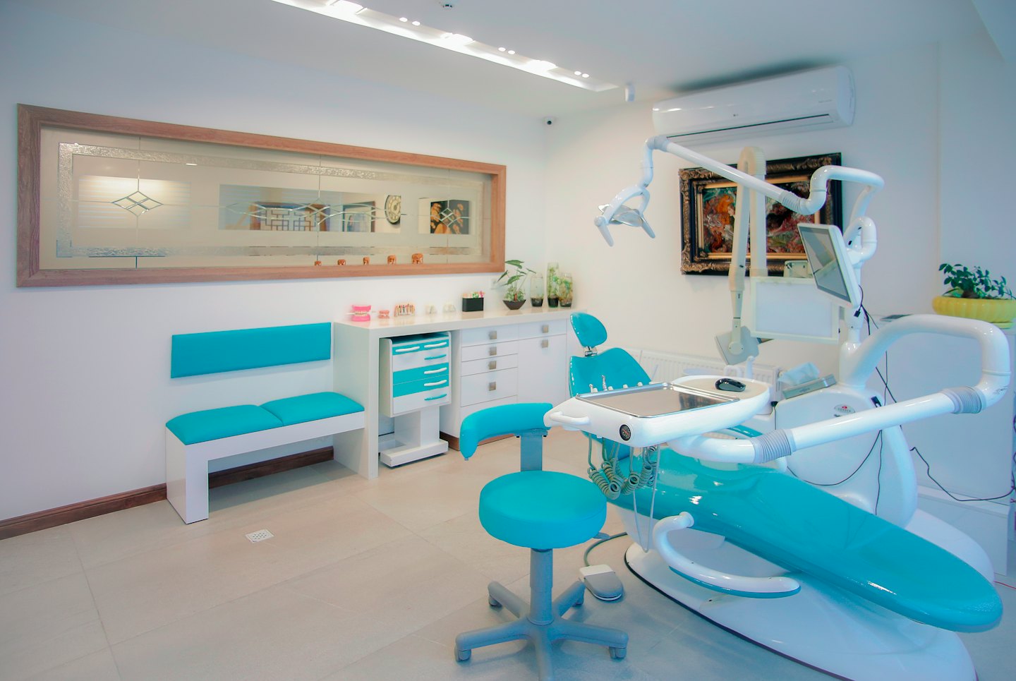 Modern dental clinic with turquoise chair and waiting bench.